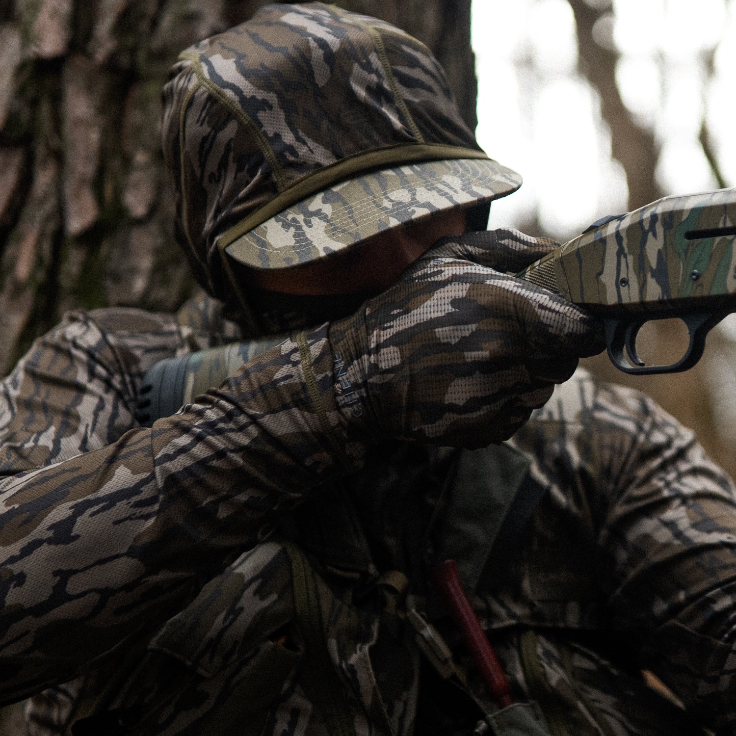Person in full camouflage gear holding a shotgun in a forest setting