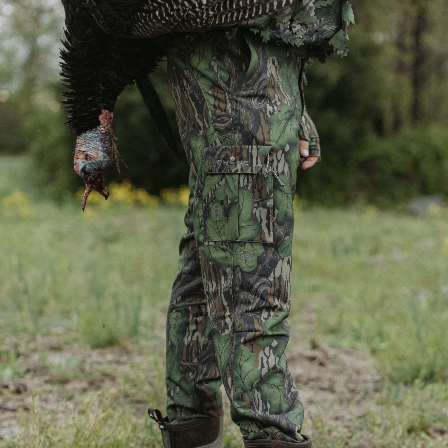 Person in camouflage clothing holding a turkey in a forest setting
