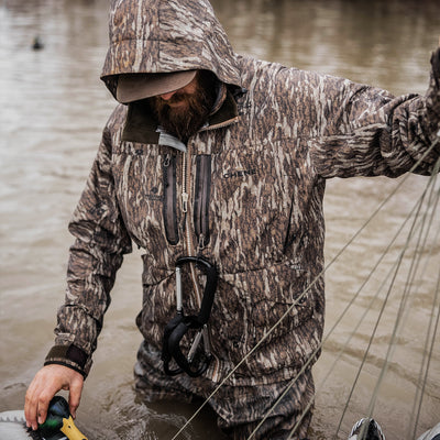 a man in a camouflage jacket holding a fish in water