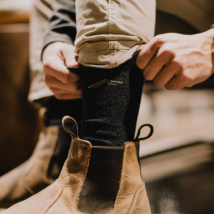 a person tying a black sock on their ankle